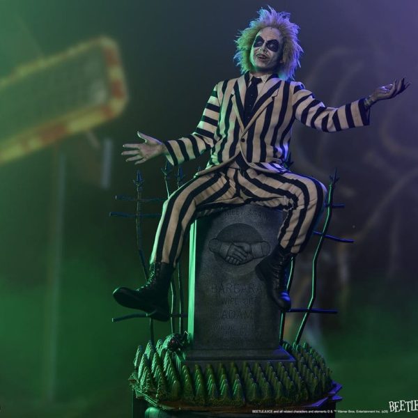 Beetlejuice figure in a striped suit sitting on a tombstone for Barbara and Adam with arms outstretched